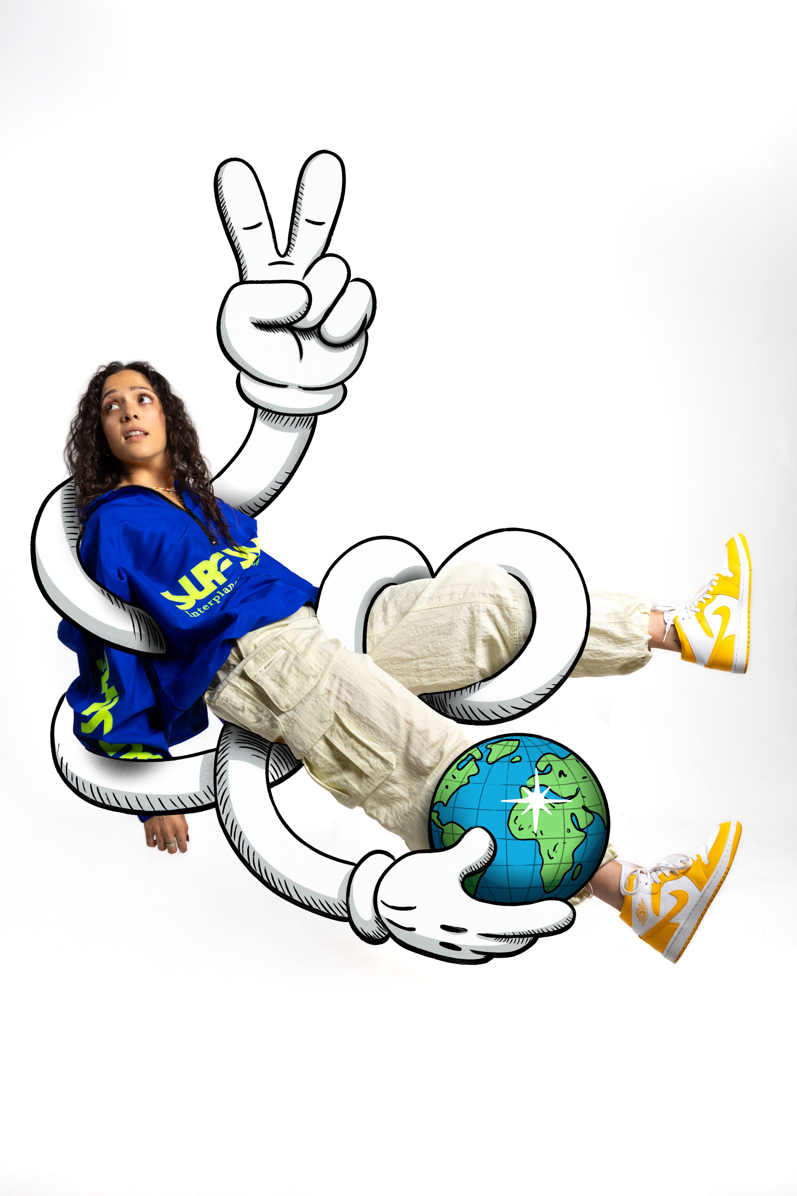 Portrait of musician Joyia sitting in a chair while a rubber-hose cartoon character wraps its arms around her and holds a illustrated globe. A large illustrated peace-sign hand extends upward, blending graphic line work with the photo in a bold, playful style.