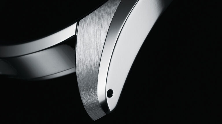 Close-up of a Grand Seiko case showing a Zaratsu-polished bevel meeting a finely brushed lug, highlighting the crisp transitions, distortion-free mirror finish, and precise craftsmanship.